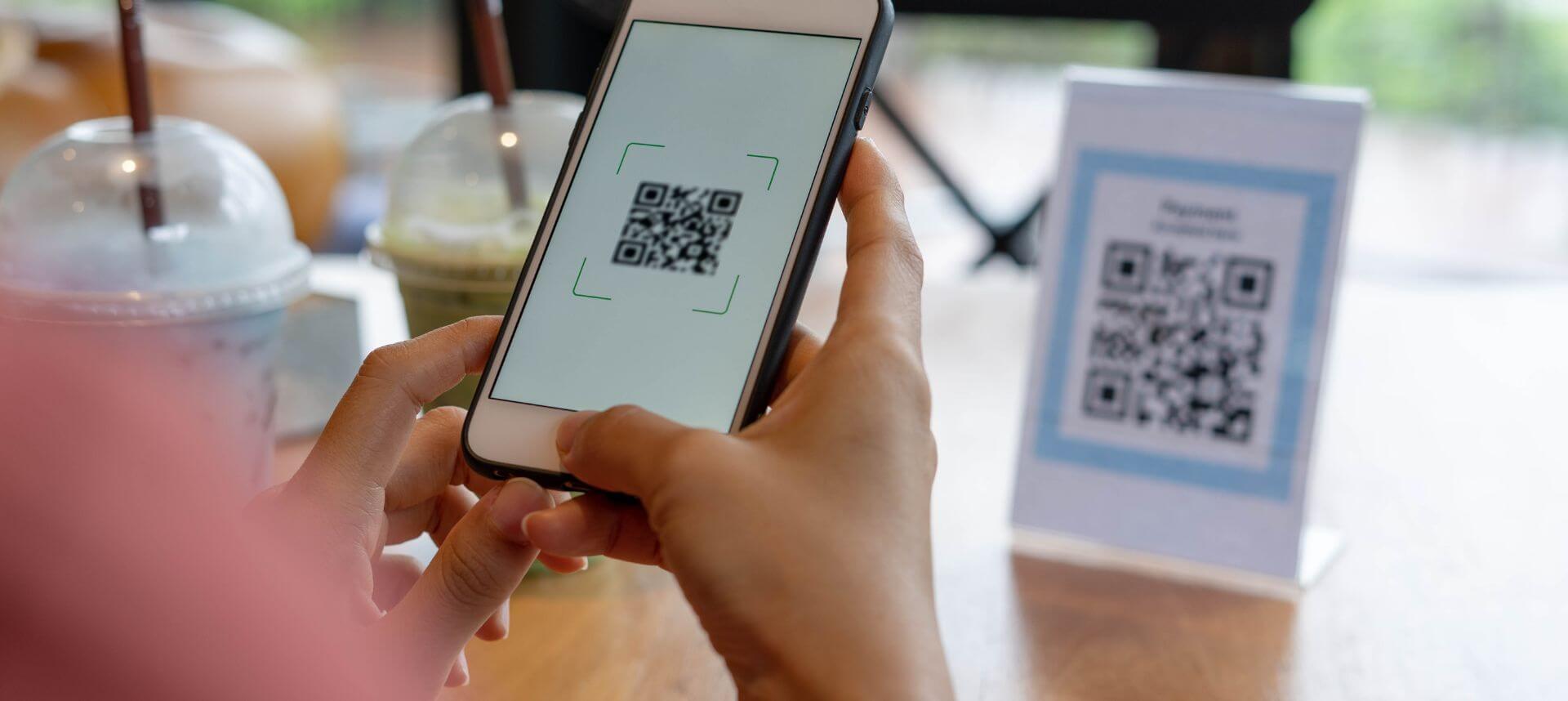 Person scanning a birthday QR code on a table, showing a digital greeting message on their phone